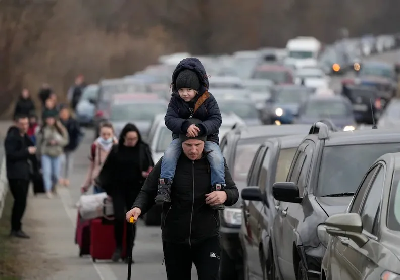 一名父親帶著孩子穿越已經無法動彈的車陣，他們抵達邊境後就即將道別。AP