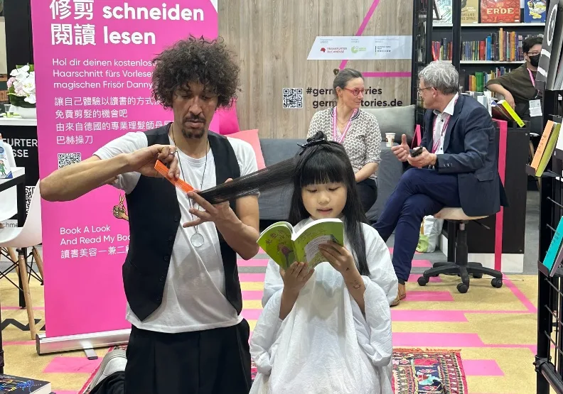 2024年台北國際書展於2月20日至2月25日，在台北世貿一館展開。圖為德國館的「讀書美容 一兼二顧」活動，民眾只要朗讀一本書，就有機會接受理髮師丹尼．波爾巴赫（Danny Beuerbach）（左）的免費理髮服務，共享閱讀美好時光。李加祈攝
