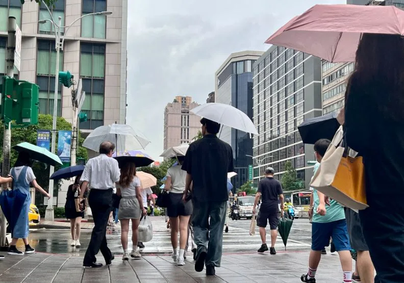 圖為雨天北市街頭撐傘民眾，遠見編輯部